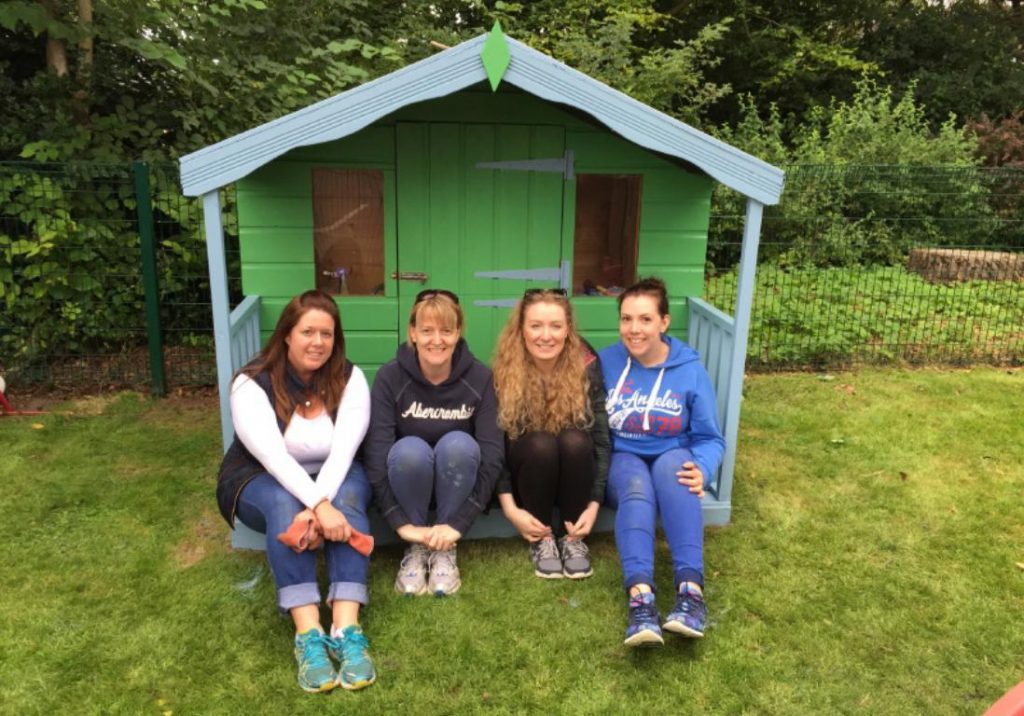 A group of people sitting under a childrens playhouse.