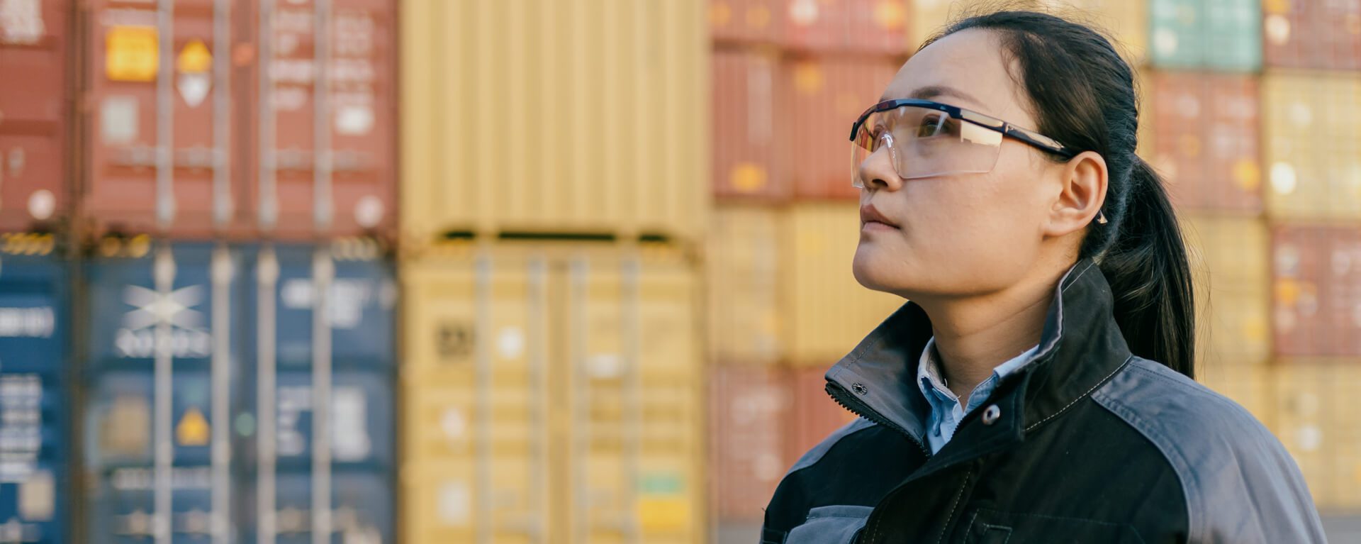 a woman wearing safety goggles and standing in front of containers
