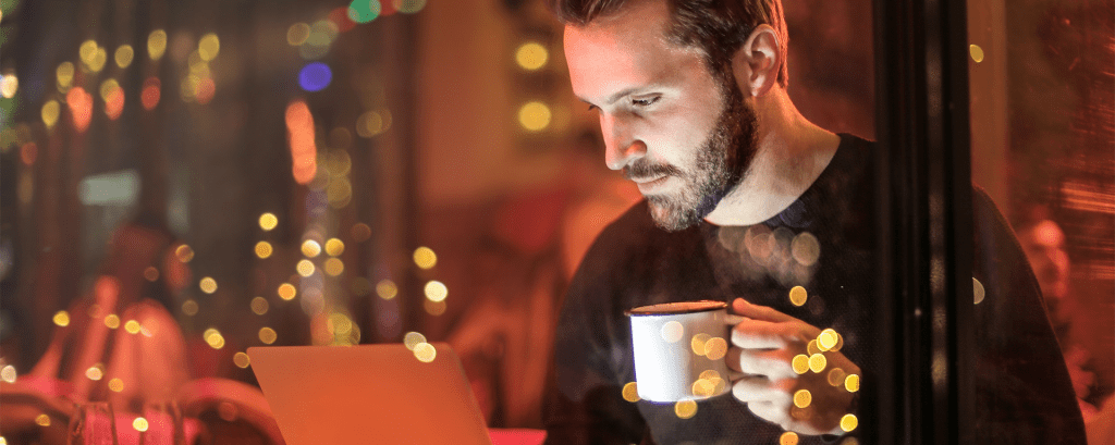 Man with coffee looking at computer.