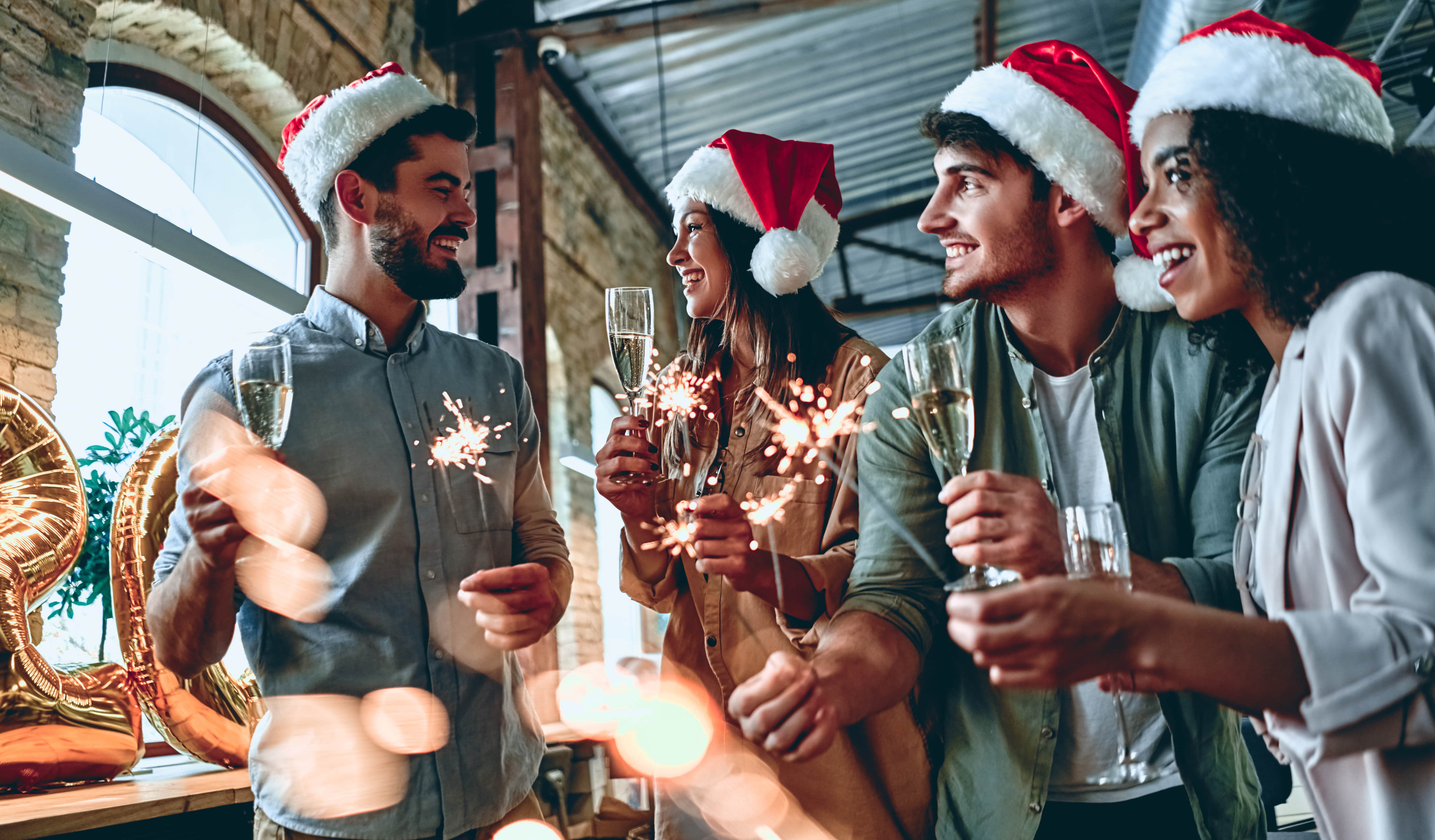 Four people at a staff Christmas party with drinks and sparklers