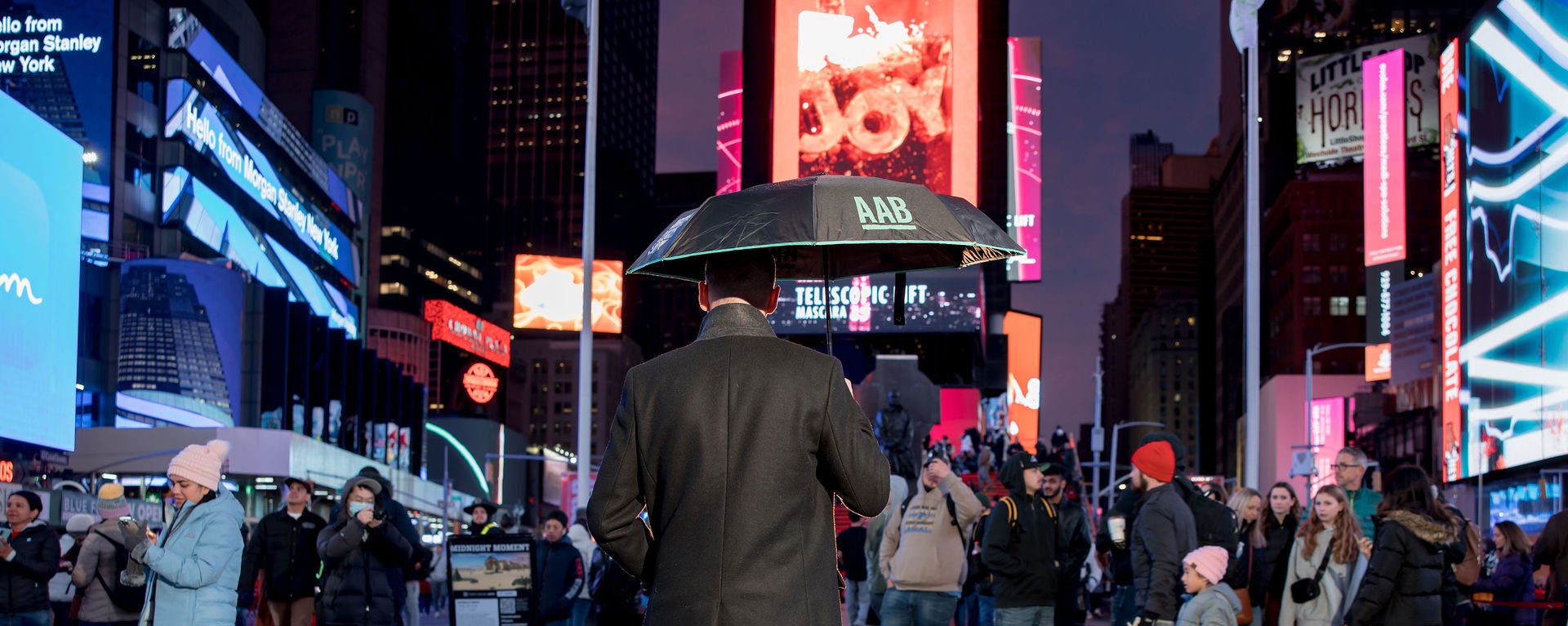 A banner for our US Payroll page, showing an AAB employee with an AAB umbrella in Times Square