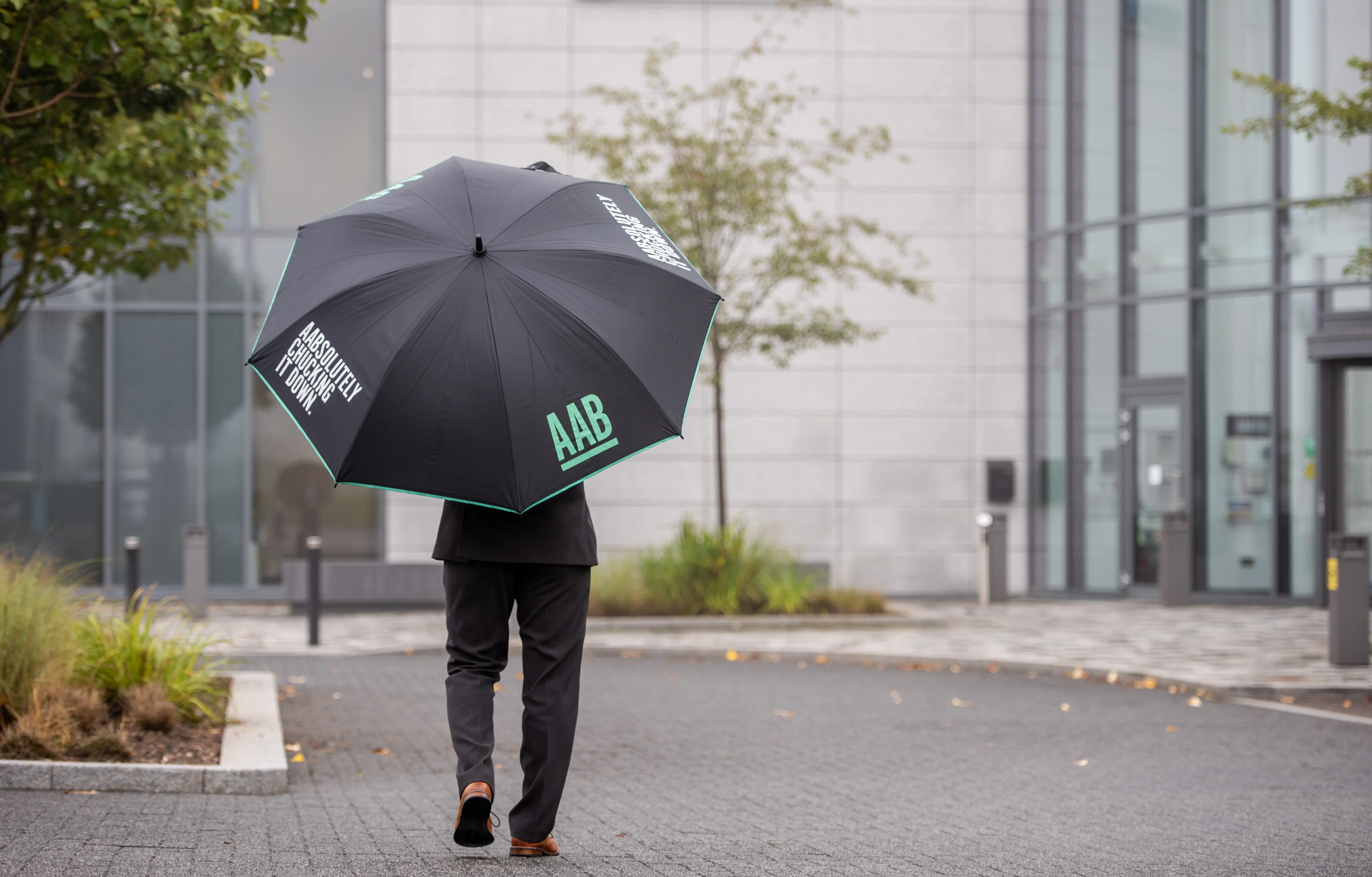 AAB team member walking outside office with umbrella