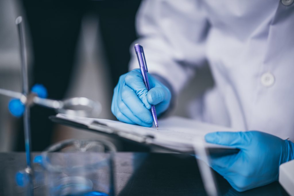 A person writing on a paper wearing blue gloves.