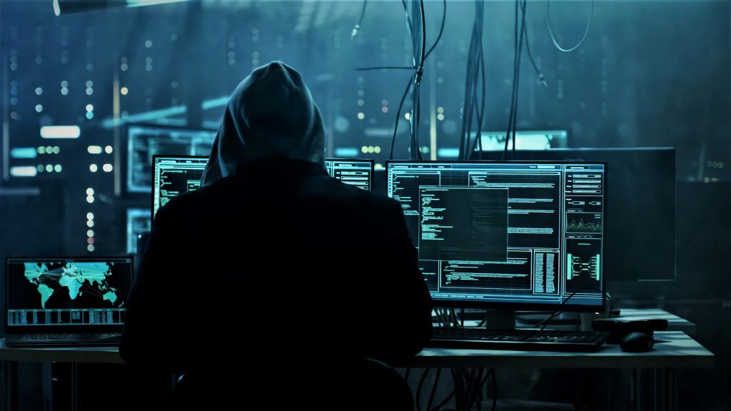 A person in a hoodie looking at a computer screen.