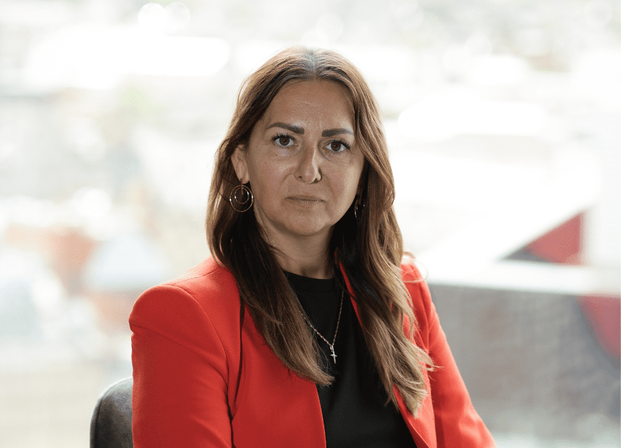 Woman in red blazer, thoughtful expression. AAB employee
