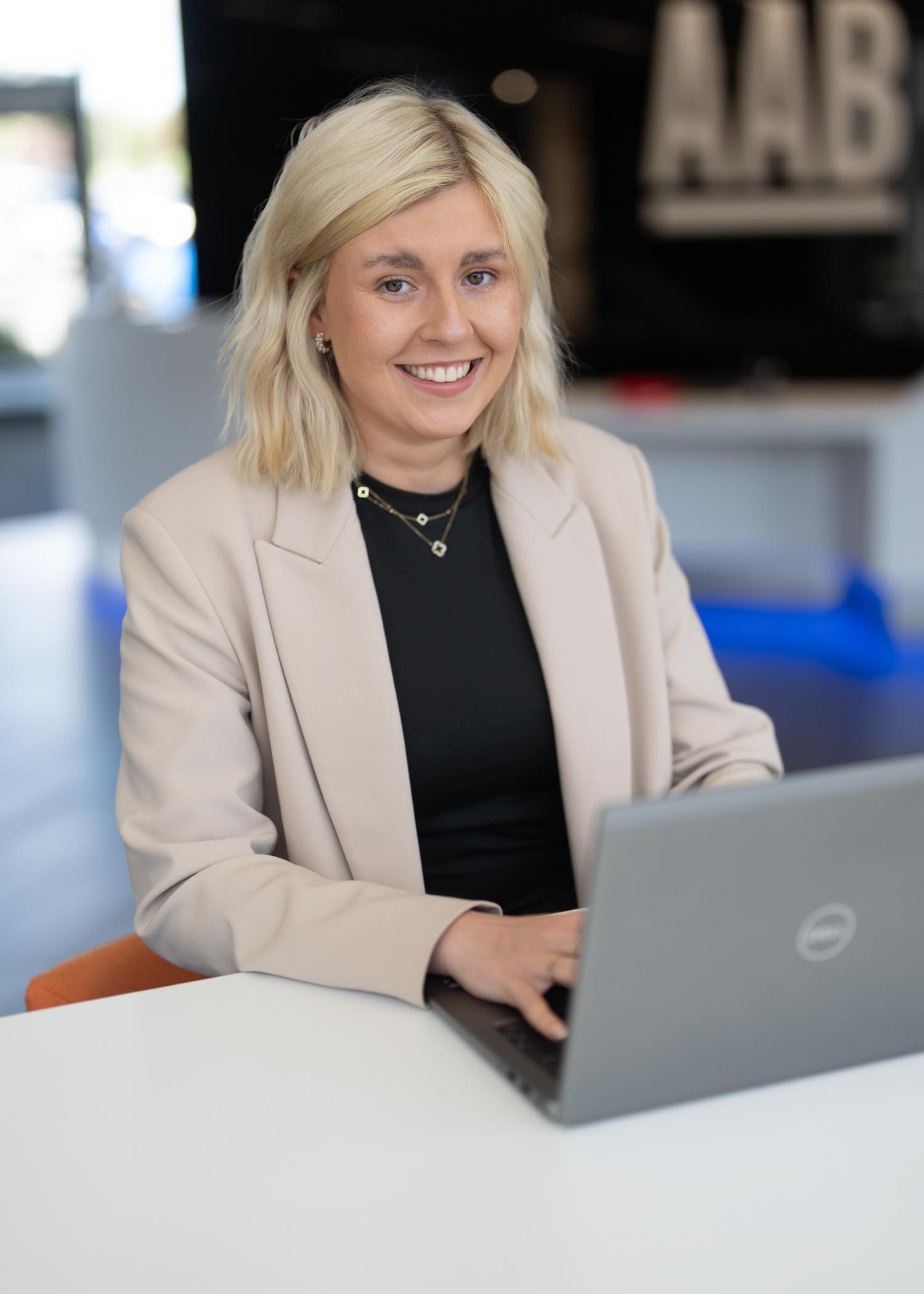 Chloe Singer smiling at camera while typing on laptop in the Aberdeen office