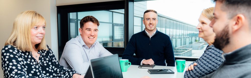 An image of AAB Employees sitting at a table and smiling together.
