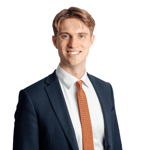 An image of Thomas Hill wearing an orange tie, white shirt and blazer. He is smiling at the camera.