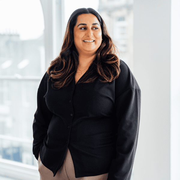 An image of Tahreem standing in the office and smiling out the window.