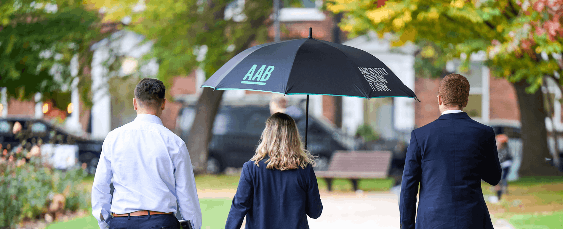 AAB employees walking with branded umbrella - hero banner